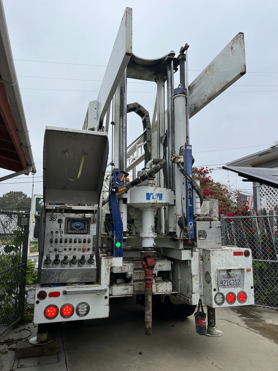 The Yeti M10 truck rig from behind, its control panel open and drill string down, parked on a driveway.